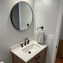 Bathroom vanity with round mirror and matte black fixtures