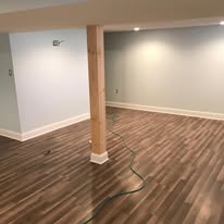 Finished basement with wood-look flooring and recessed lighting